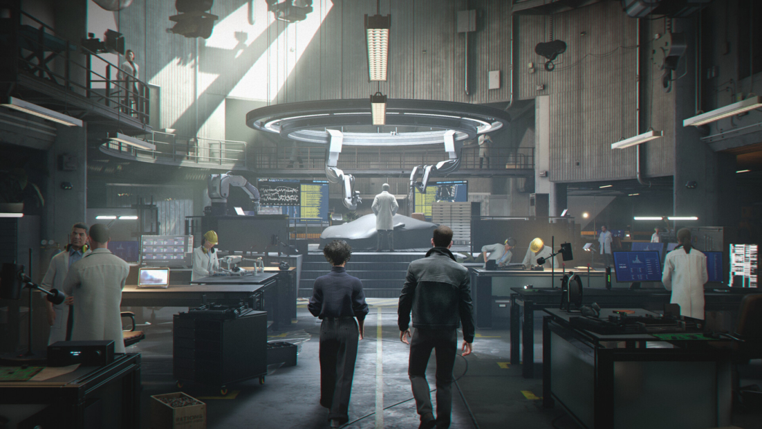 007 First Light Tips: Two people walk toward a central illuminated platform in a large modern laboratory with multiple workstations and technical equipment