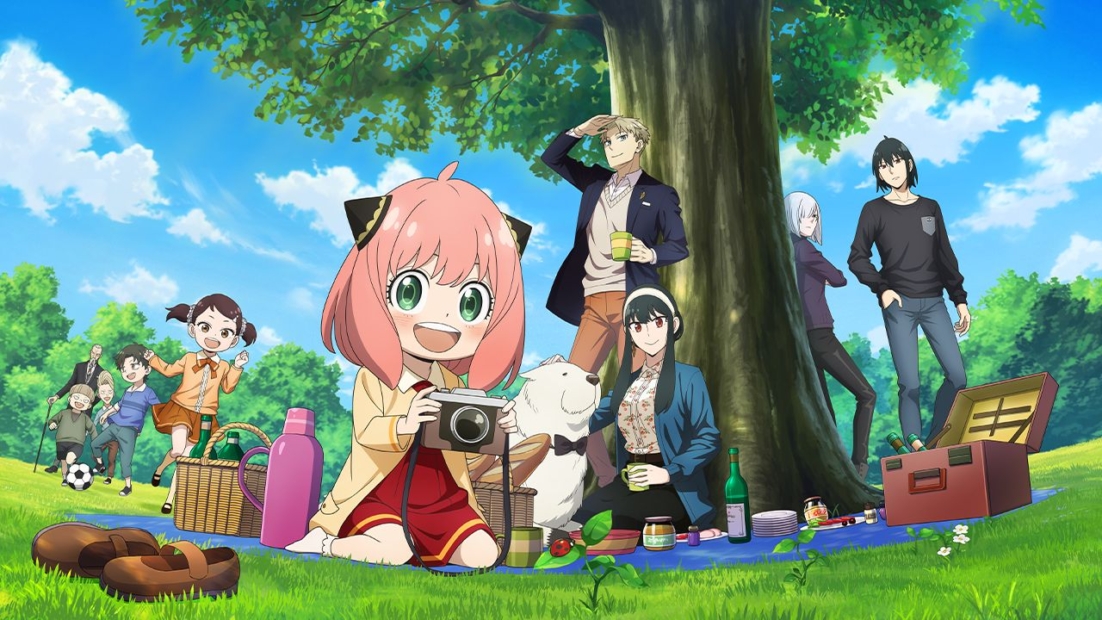 Gruppe von Personen und einem Hund sitzt auf einer Wiese unter einem großen Baum, ein Mädchen mit rosa Haaren hält eine Kamera in der Hand