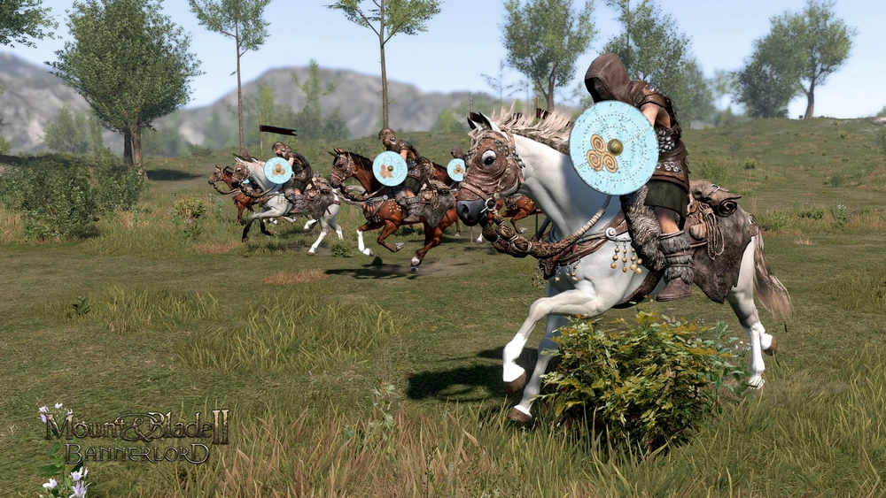 Mehrere berittene Krieger der Battania-Fraktion aus Mount & Blade 2 Bannerlord reiten in einer Linie über eine Wiese, jeder mit rundem Schild und Kapuzenumhang.