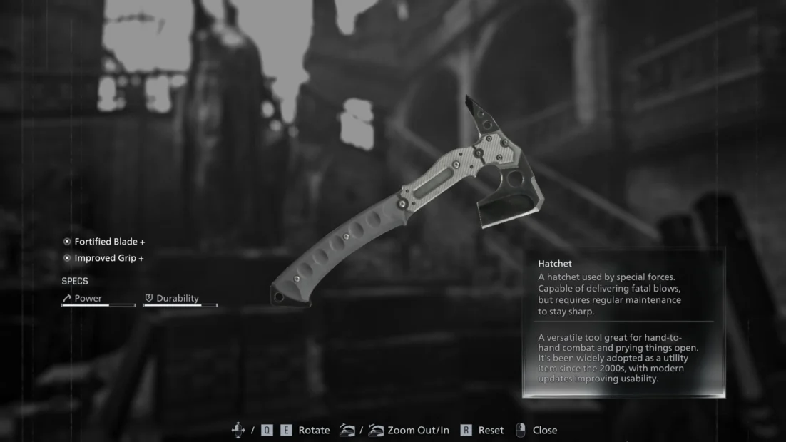 Close-up of a tactical hatchet with a perforated handle and serrated blade against a blurred background