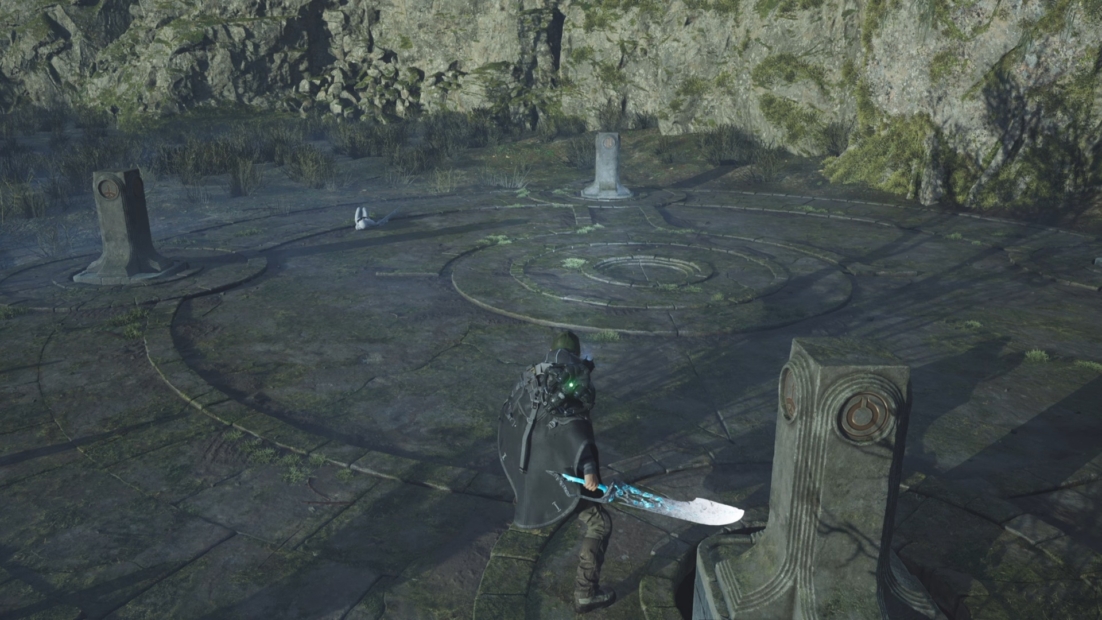 A character from the game 'Hell is Us' stands in a circular arena with three pillars. The character wears a black cloak and holds a large, glowing sword.