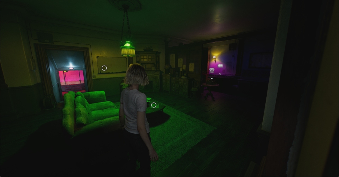Person standing in a dark room with a green couch and two windows showing red and yellow light