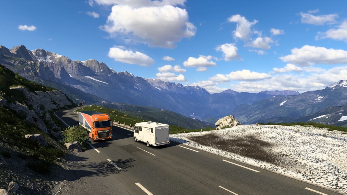 Orange semi-truck and white camper driving on mountain road with rocky cliffs and snow patches in Euro Truck Simulator 2