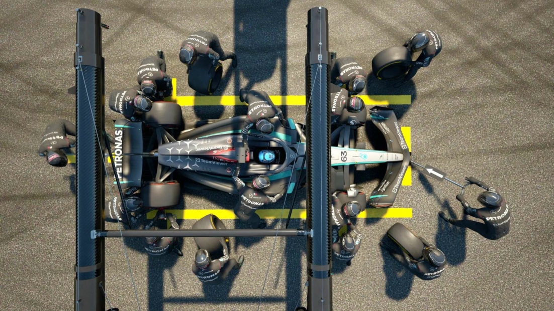 Blick von oben auf einen Formel-1-Wagen in der Boxengasse, umgeben von einem Team von Mechanikern, die einen Reifenwechsel und Wartungsarbeiten durchführen.