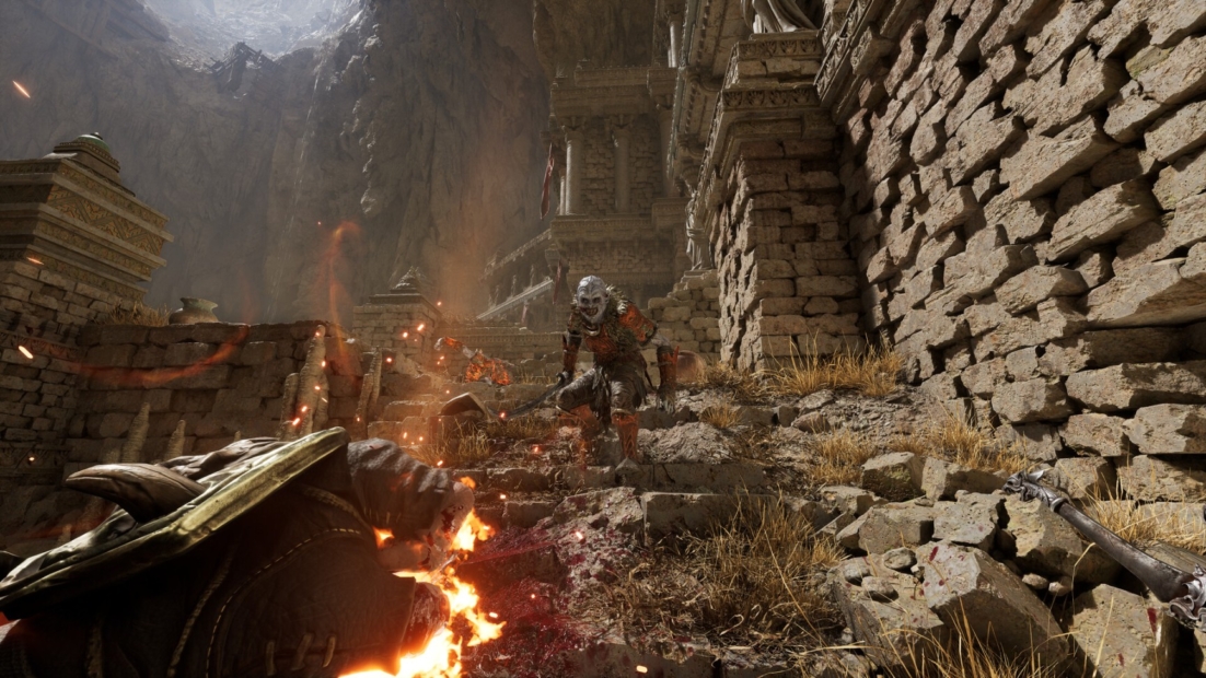 Skeleton warrior in armor with sword stands on rocky stairs facing a burning figure in a rocky ruins setting