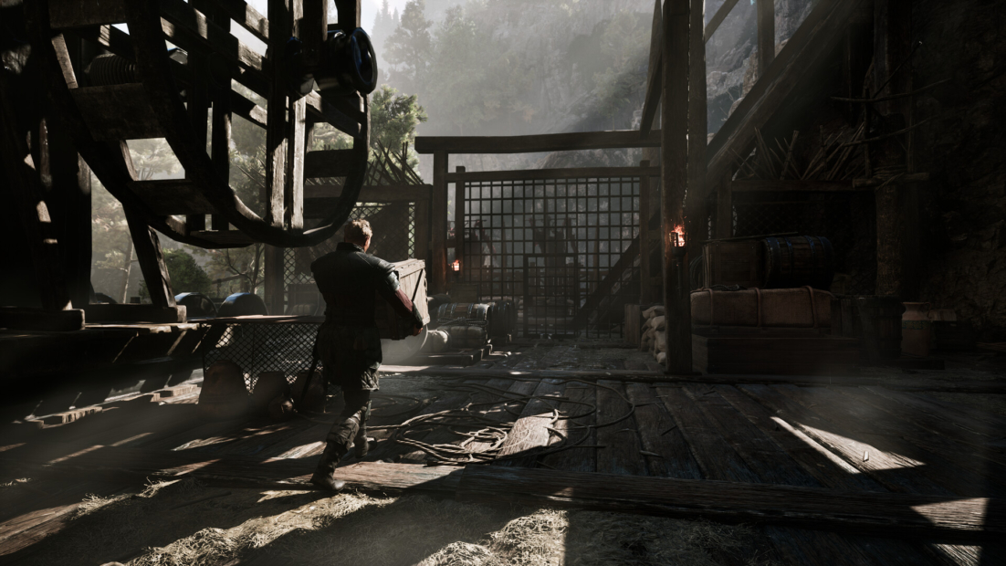Person in medieval clothing carrying a crate inside a dimly lit workshop surrounded by wooden structures with beams of light in the background