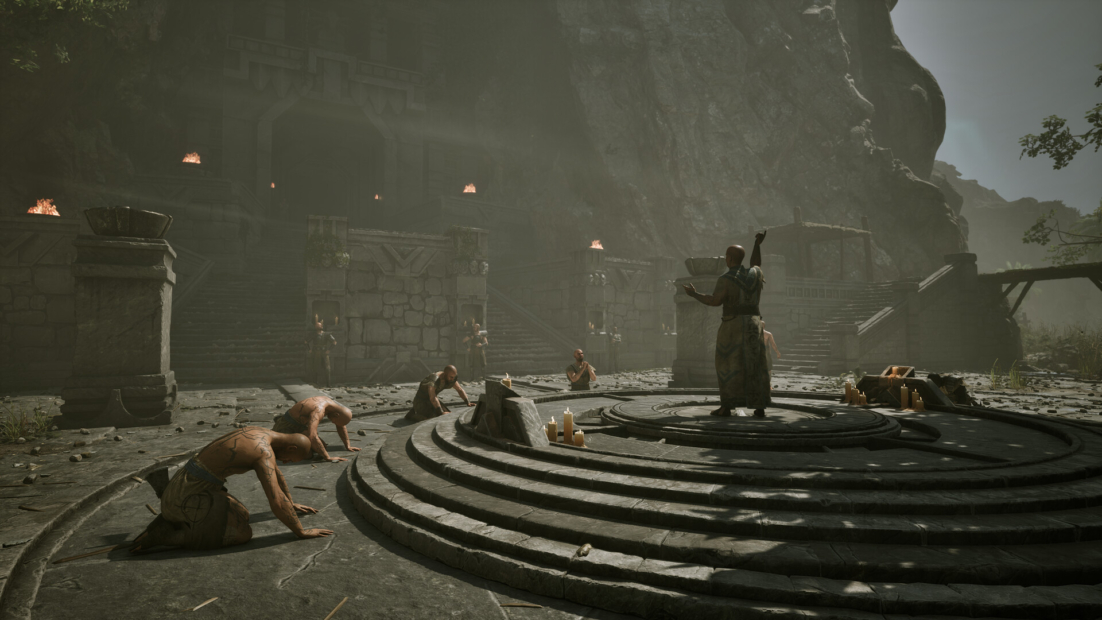 Several people kneel on a stone circular platform before a person standing with raised arms, surrounded by rocks and ruins.