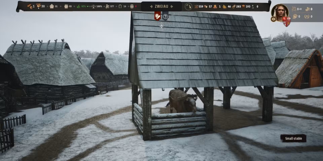 Village scene with multiple thatched-roof buildings and one shingle-roofed stable housing an ox, surrounded by wooden fences.