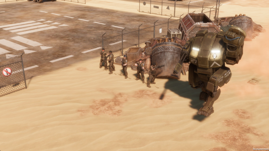 Several soldiers stand in a sandy area next to a large armored combat robot with two cannon arms