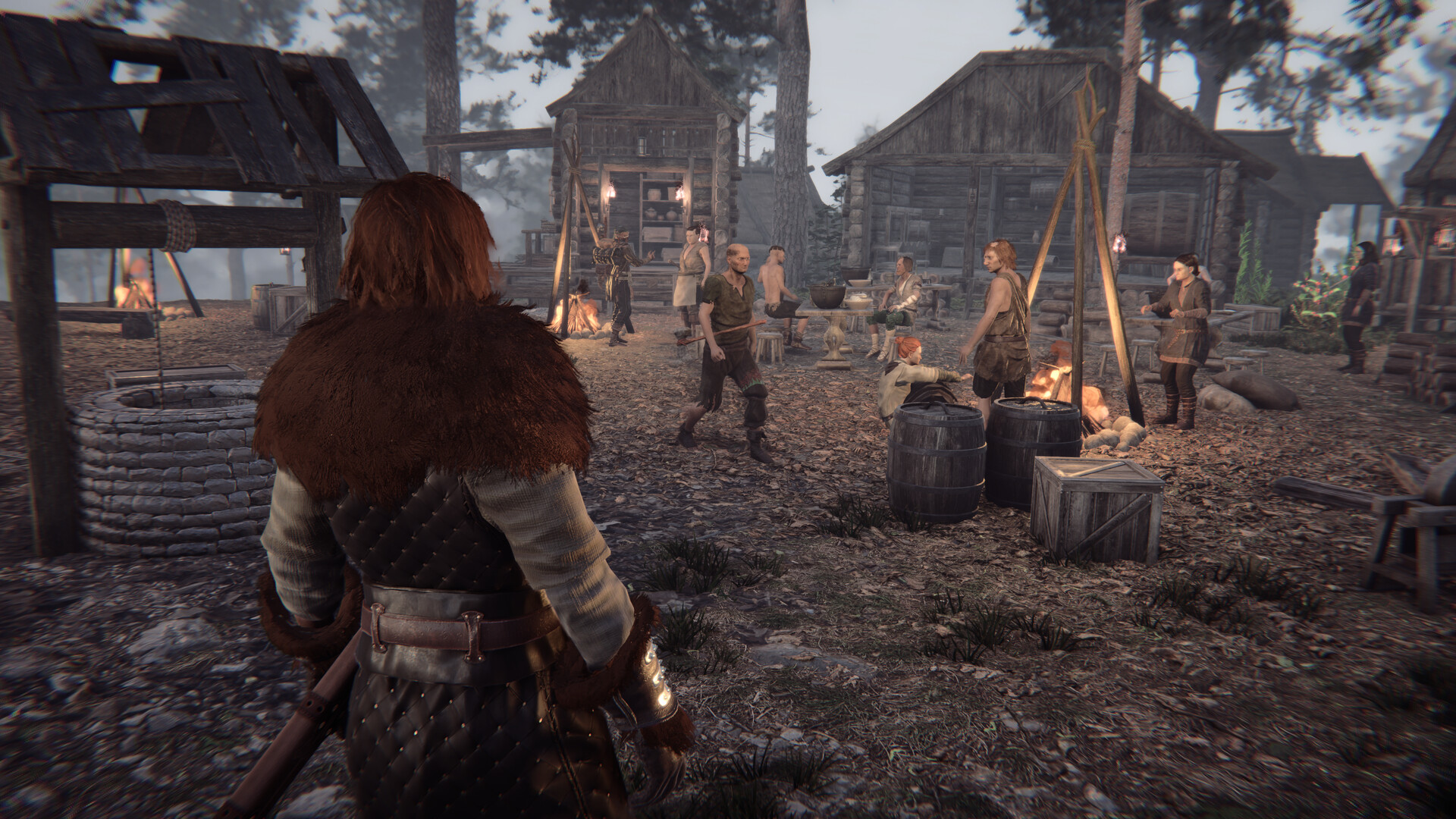 A group of nine people in medieval clothing gathered around a campfire in front of three wooden houses in a forest.