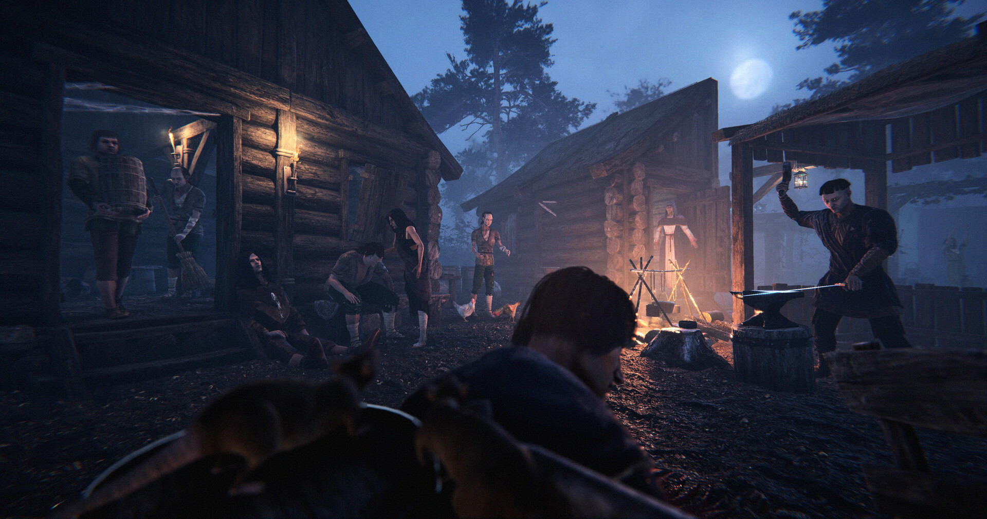 Several people in medieval clothing gather around a campfire at night in front of wooden cabins under a full moon.