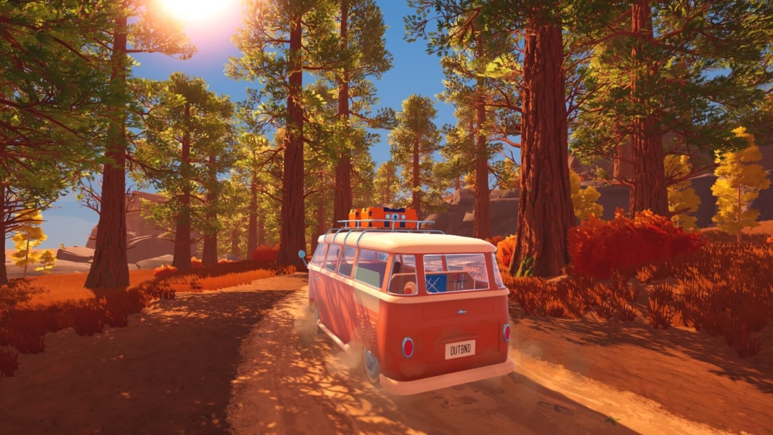 View from inside a vehicle showing a forested landscape with mountains in the background and an arm extending out the window