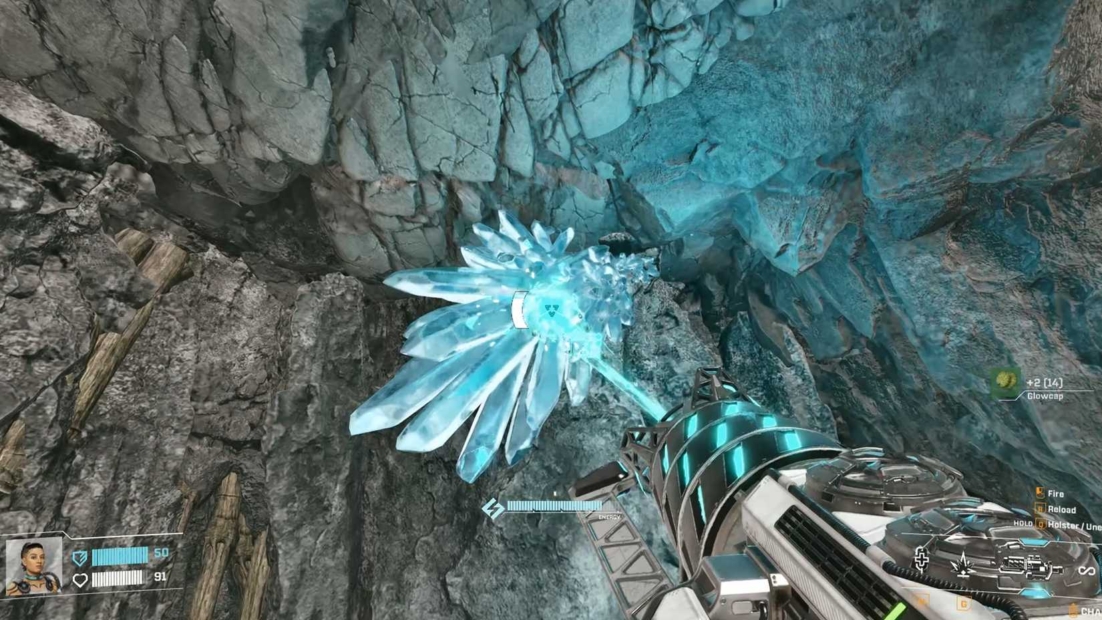 View of a rock wall with a glowing, crystal-like object held by a mechanical device.