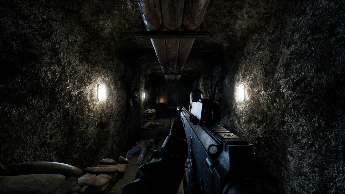 First-person view of a rifle in a dark narrow tunnel with uneven rock walls and illuminated wall lamps