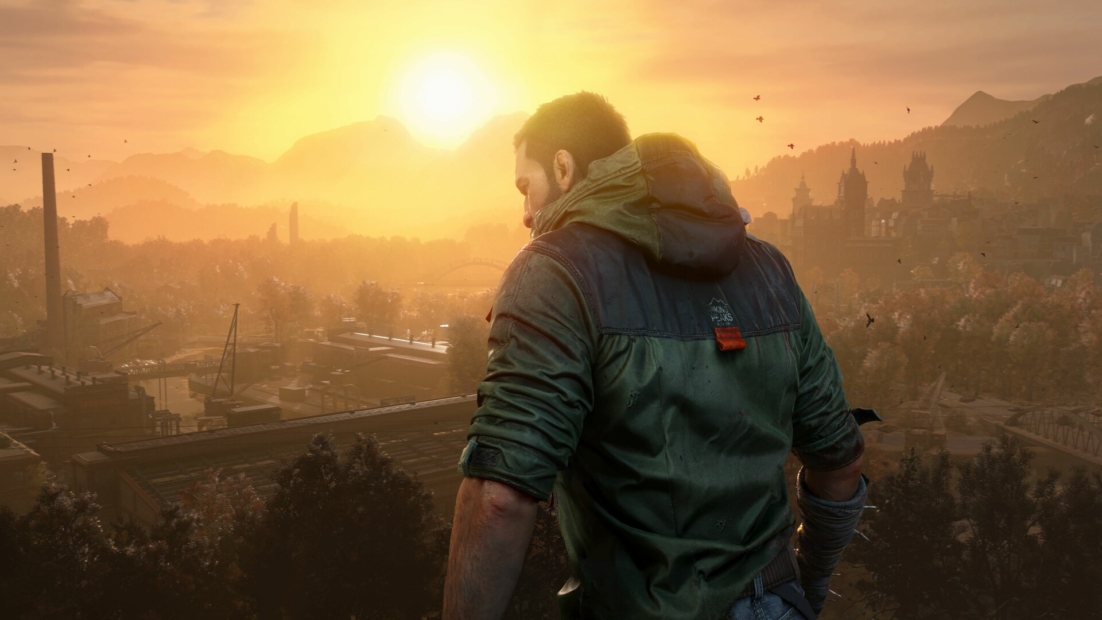A man in a green jacket stands with his back to the camera, looking at a landscape during sunset. Mountains and a city are visible in the background.