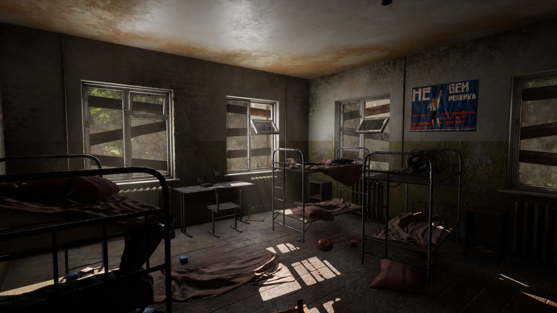 Dim room with several metal beds, broken windows, and a poster on the wall